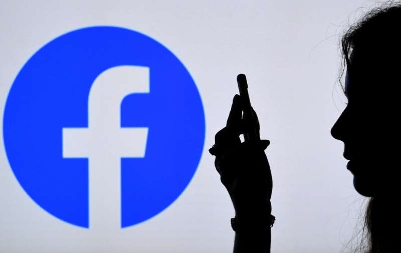 En esta ilustración fotográfica, una persona mira un teléfono inteligente con el logotipo de una aplicación de Facebook que se muestra en el fondo, el 17 de agosto de