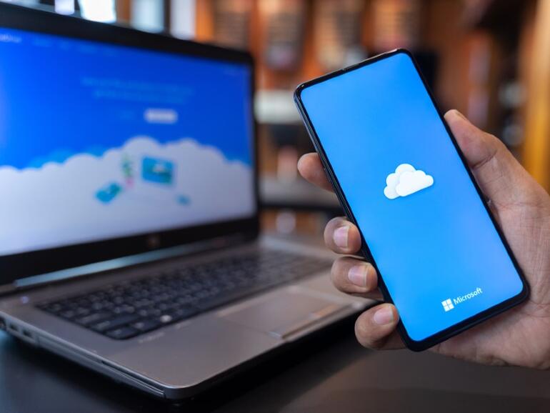 Hombre sujetando Xiaomi Mi Mix 3 con OneDrive en pantalla.  Microsoft OneDrive es un servicio de alojamiento de archivos que permite a los usuarios sincronizar archivos.