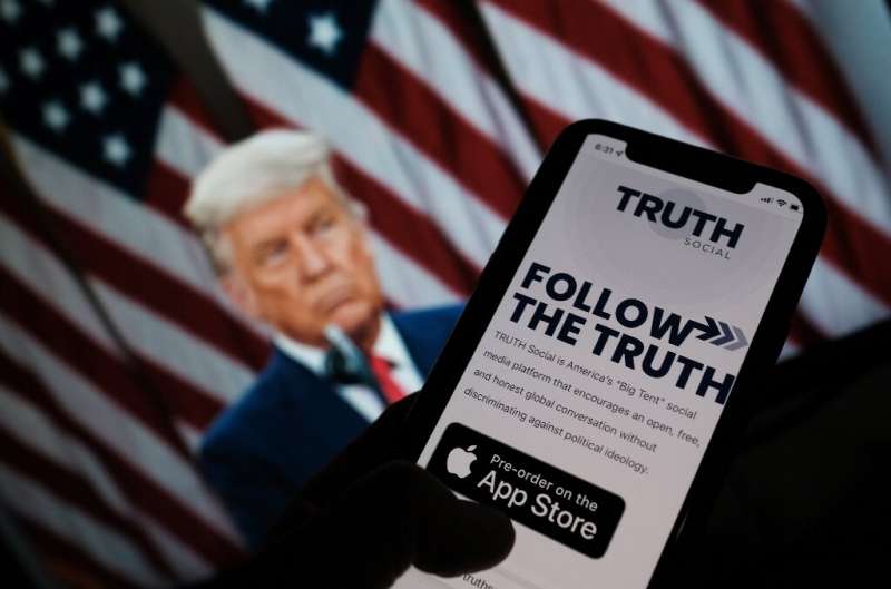 La nueva aplicación 'Truth Social' de Donald Trump se ve en la pantalla de un teléfono inteligente antes de una foto del ex presidente