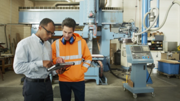 Ingenieros de fabricación interactuando, tablet en mano.