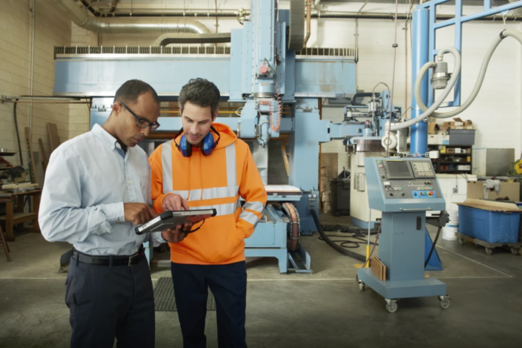 Ingenieros de fabricación interactuando, tablet en mano.