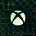 El logotipo de Xbox X en un círculo sobre un fondo oscuro con líneas verdes.