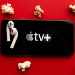 Apple TV Plus logo on phone surrounded by popcorn