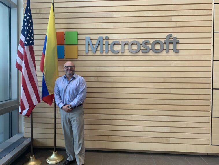Joseph parado frente a una pared con una pancarta de Microsoft.
