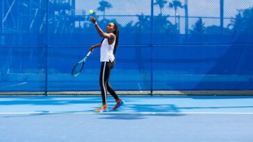 Mujer lanza una pelota de tenis en el aire