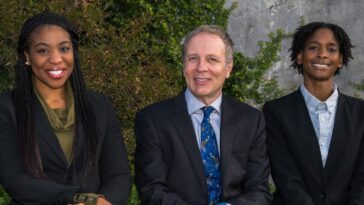 Tres personas se sientan afuera sonriendo