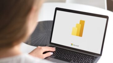 Una persona cargando Microsoft Power BI en una computadora portátil.