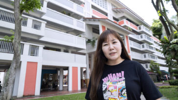 Una mujer se para frente a un edificio de apartamentos.