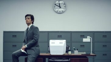 Mark Scout sits on the edge of a Lumon desk with a plaster on his head in Severance season 1, which arrived before Severance season 2