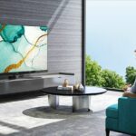 A man watching a Hisense TV in a modern looking living room.