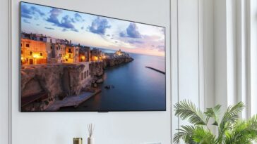 The LG G3 OLED mounted on a white wall displaying a scene from a coastal town