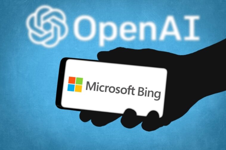 Mano sombría sosteniendo un teléfono inteligente con Microsoft Bing sobre un fondo azul con el logotipo de OpenAI