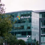 El logotipo de Microsoft se muestra de manera destacada en el exterior de un edificio de vidrio de varios pisos.