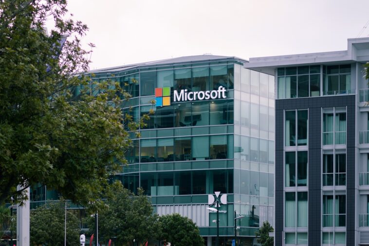 El logotipo de Microsoft se muestra de manera destacada en el exterior de un edificio de vidrio de varios pisos.